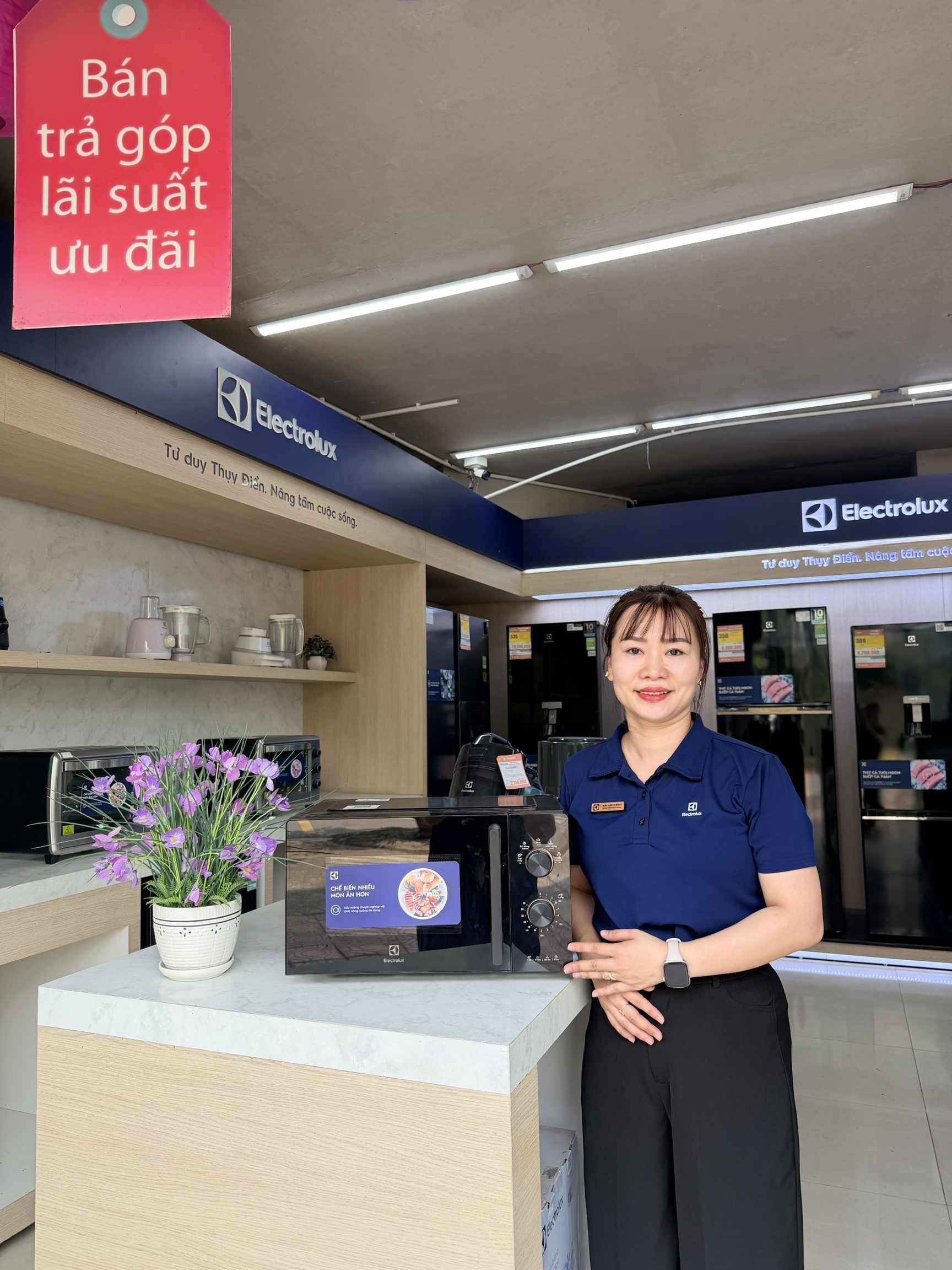 Nhân viên giới thiệu lò vi sóng Electrolux màu đen tại cửa hàng điện máy